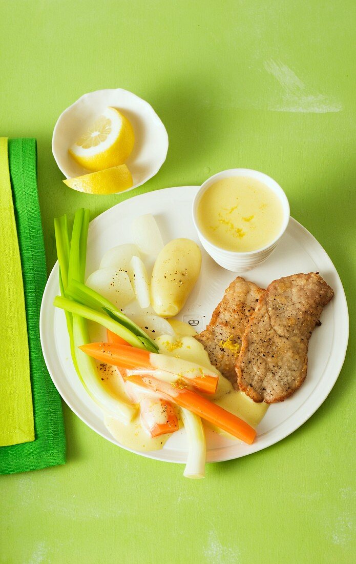 Panierte Schnitzel mit Gemüsebeilage und Zitronensauce