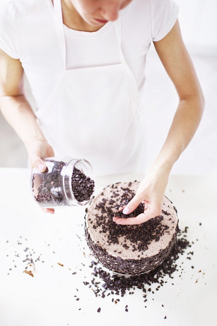 Woman sprinkling chocolate chips on cake