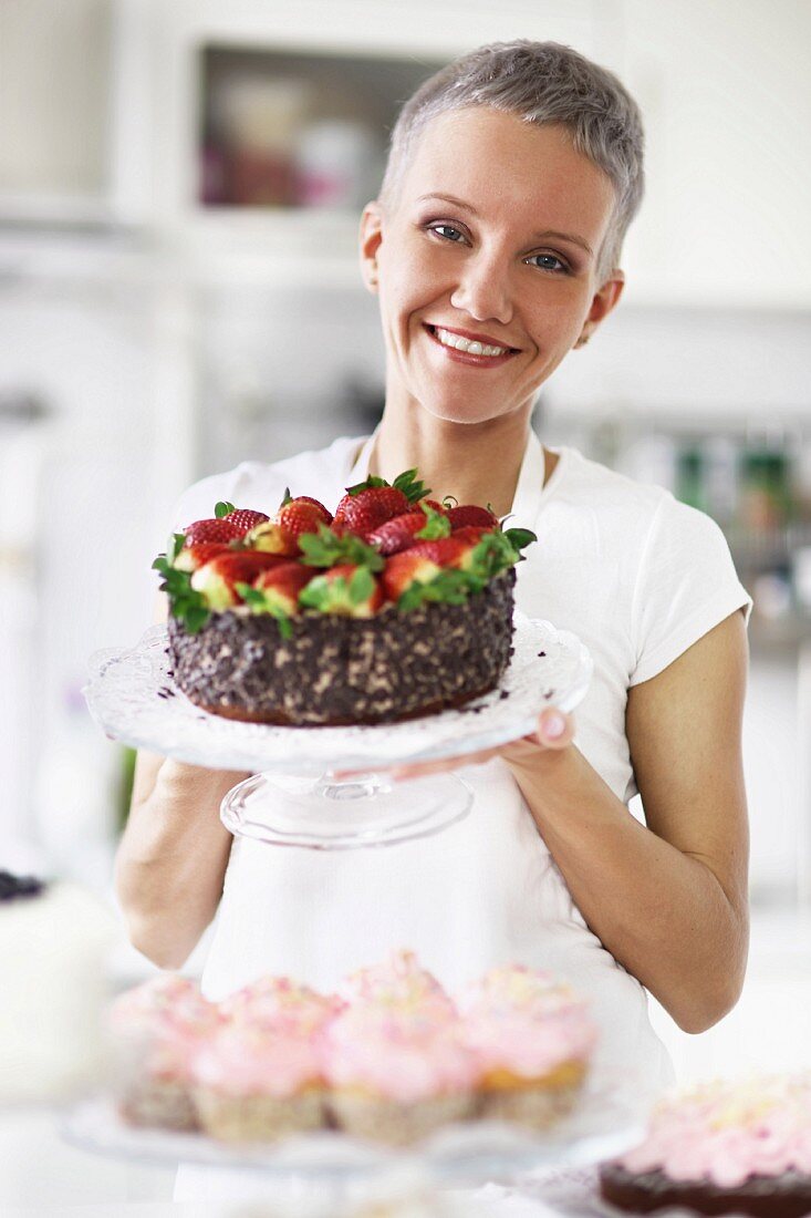 Junge Frau präsentiert Erdbeer-Schoko-Torte