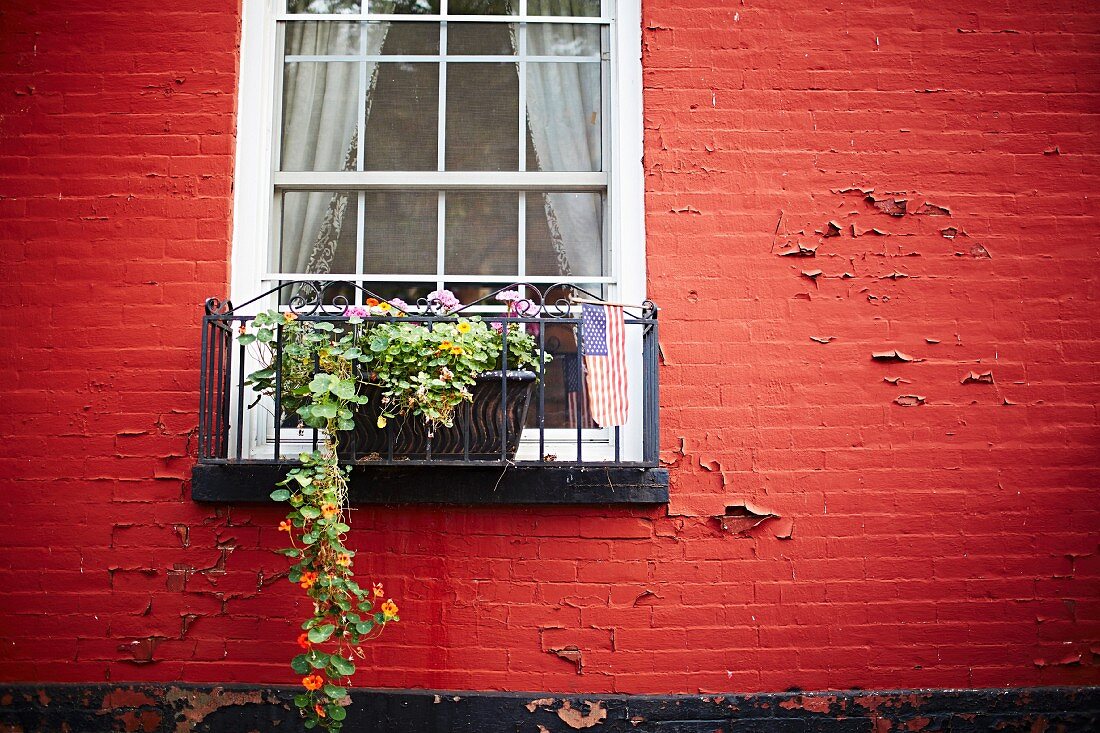 Rote Hausfassade mit Fenster, Blumenkasten & amerikanischer Flagge