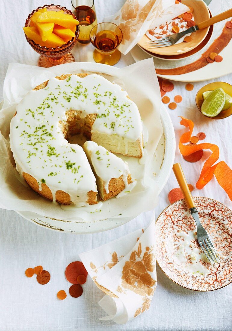 Limetten Angel Food Cake mit Holunderblüten-Glasur, serviert mit Mangospalten