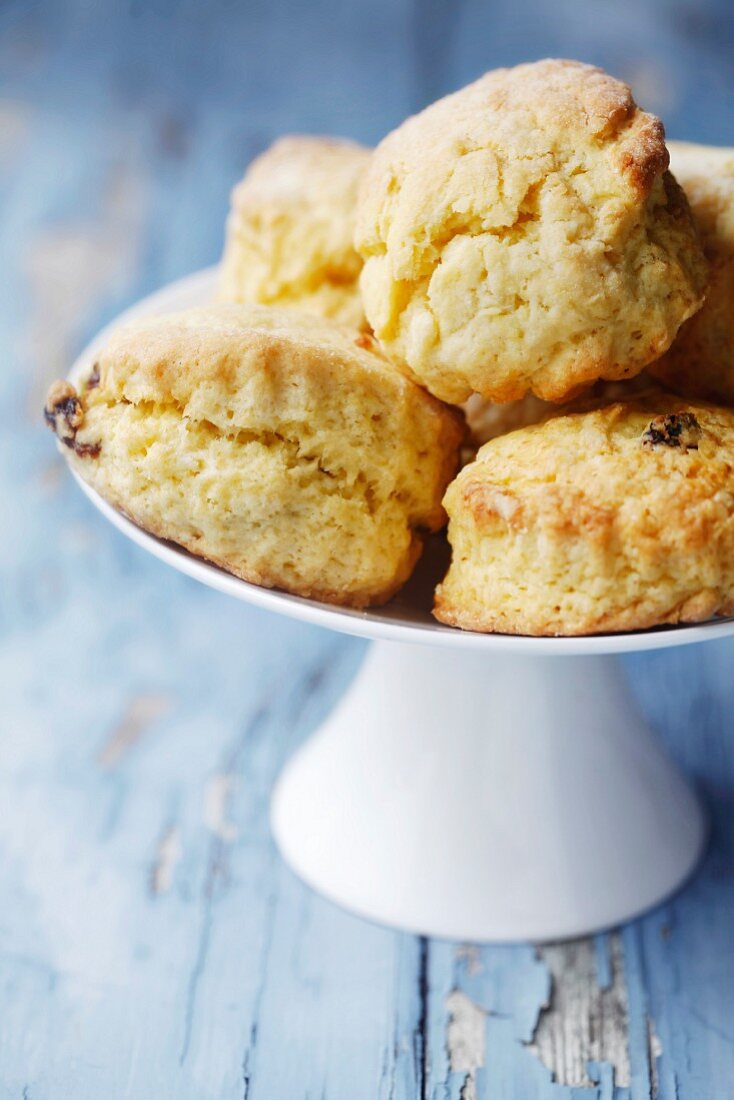 Selbstgebackene Scones auf einem weißen Kuchenständer auf blauem Holzuntergrund