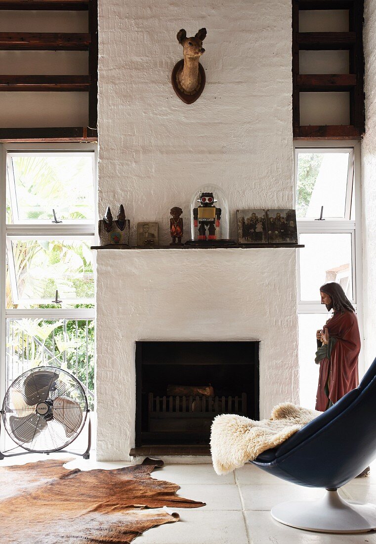 Comfortable shell chair with sheepskin in front of open fireplace in modern country house