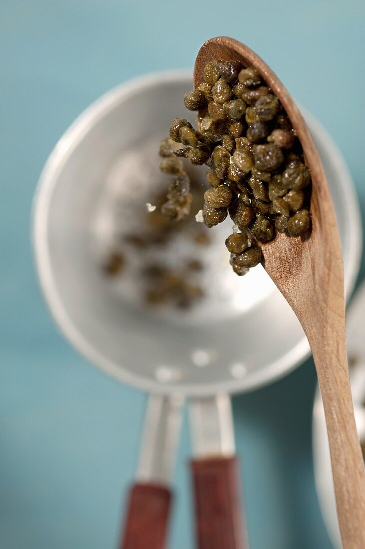 Capers on a wooden spoon