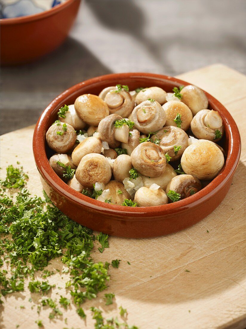 Gebratene Champignons mit Petersilie in einem Tapas-Schälchen