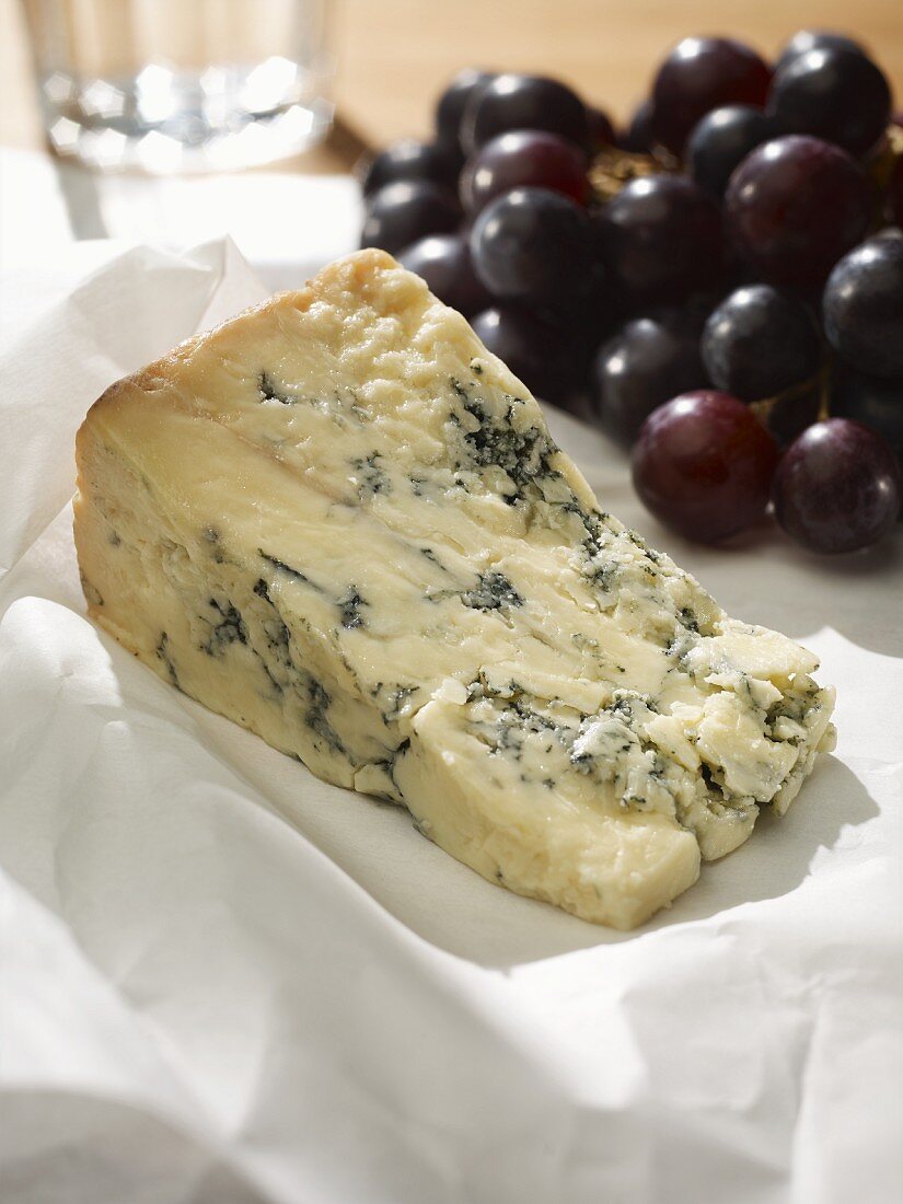 Blue Stilton on white baking parchment, with red grapes