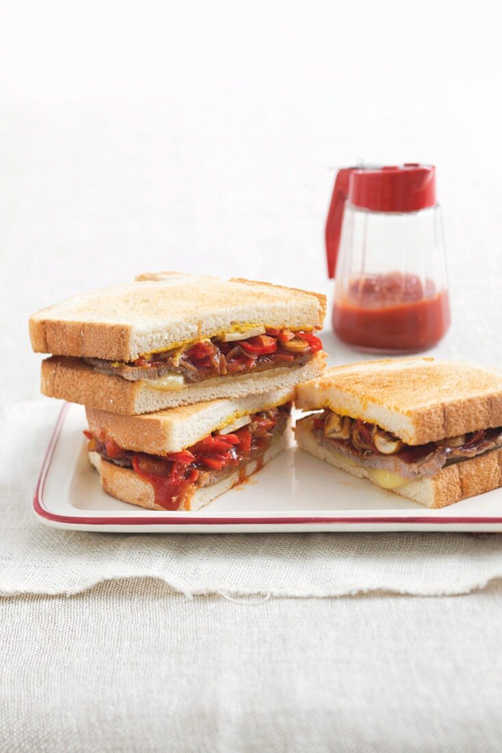 Sandwiches with beef steak, peppers, cheese and tomato sauce