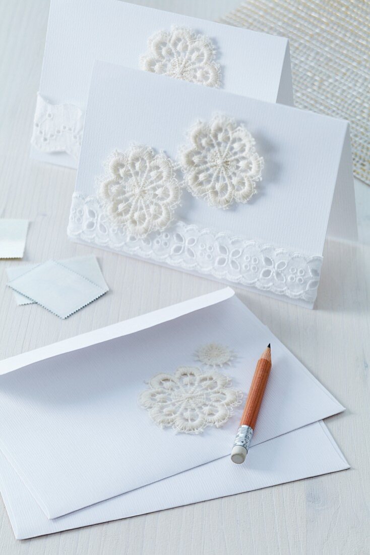 Invitation cards and envelopes decorated with segments of crocheted doily and lace trim