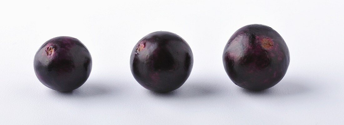 Three acai berries against a white background