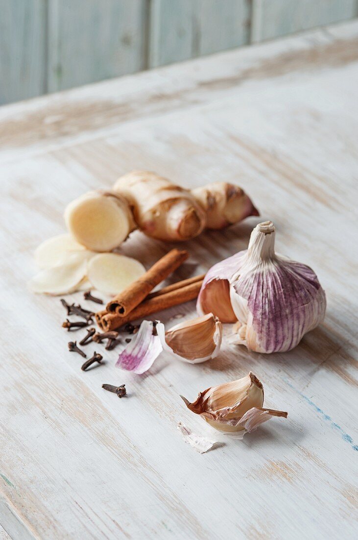A still life featuring garlic, ginger, cinnamon and cloves