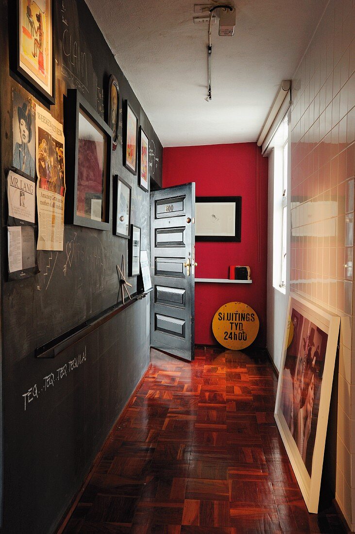 Narrow hallway with framed photos on wall painted with chalkboard paint and old mosaic parquet floor