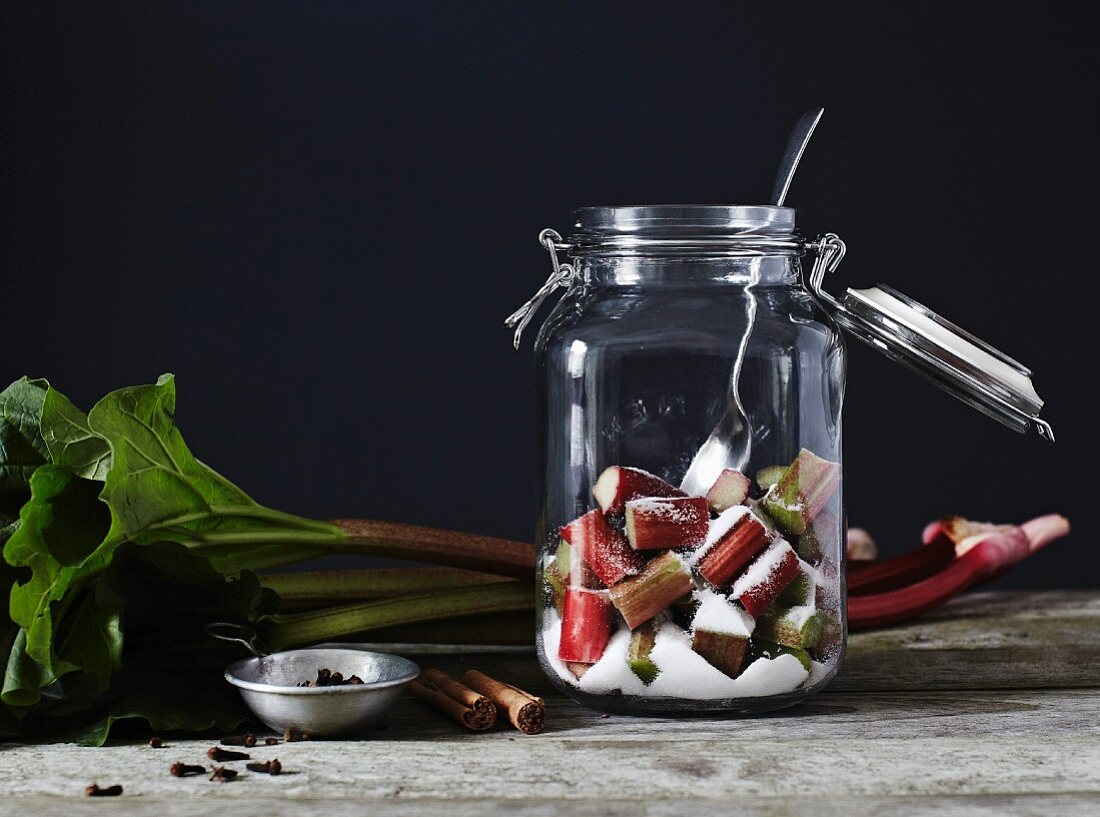 Chopped rhubarb and sugar, in an open kilner jar with a metal spoon