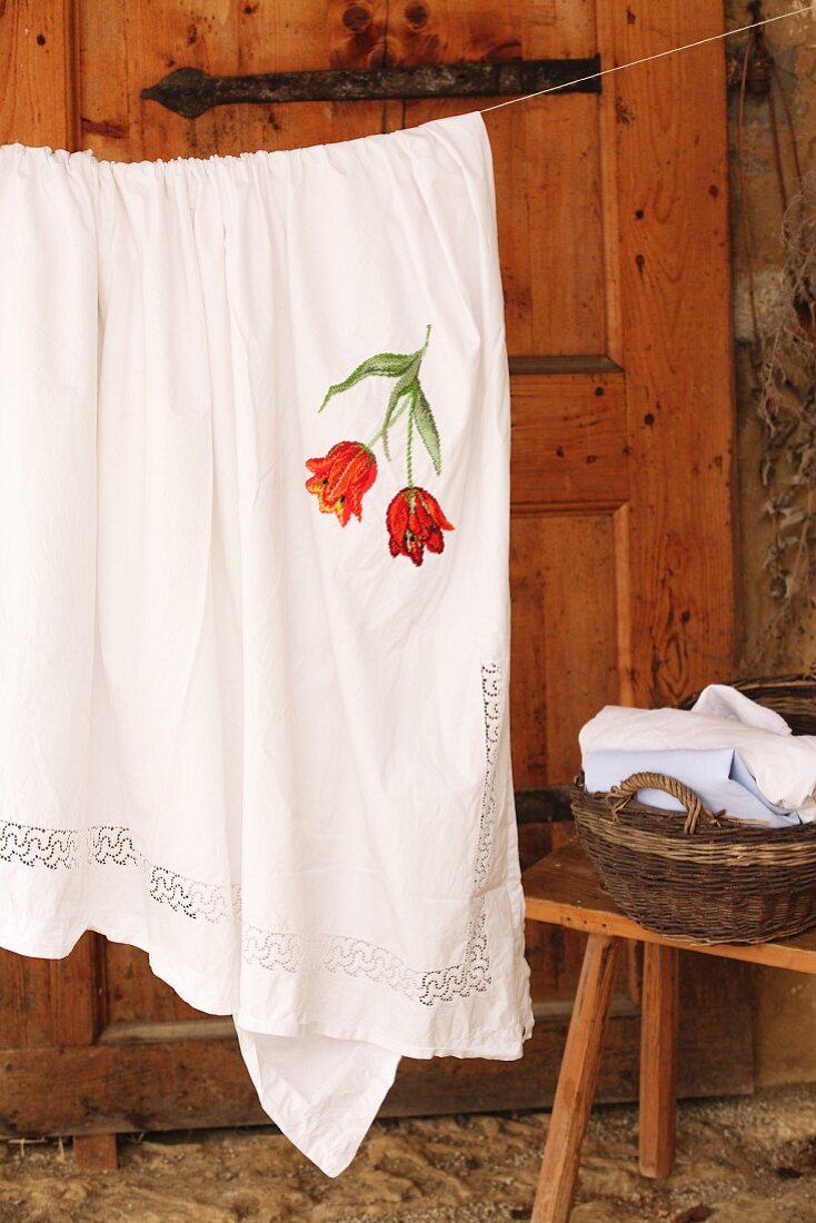 Tablecloth with embroidered floral motif hanging on washing line