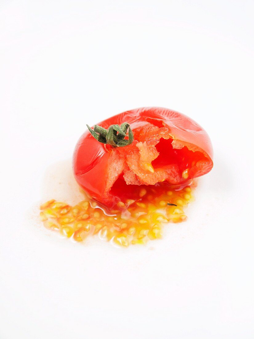 Ausgedrückte Tomate vor weißem Hintergrund