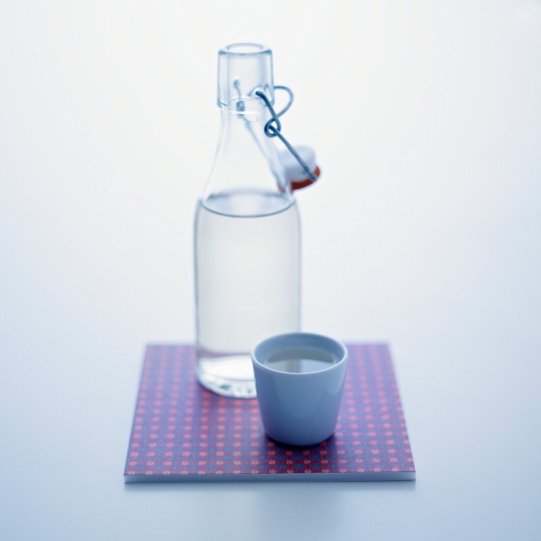 A stoppered bottle and a cup of water