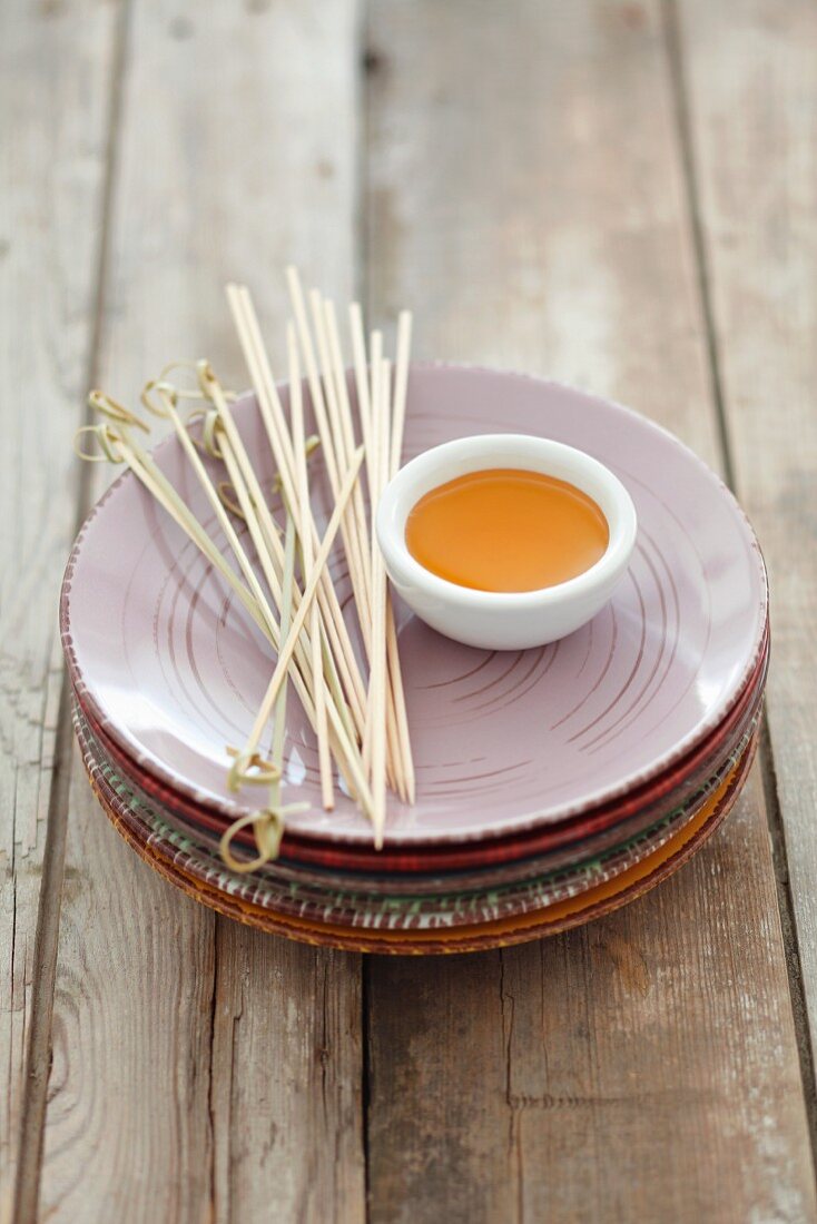 Plates, a small dish of honey, and wooden skewers