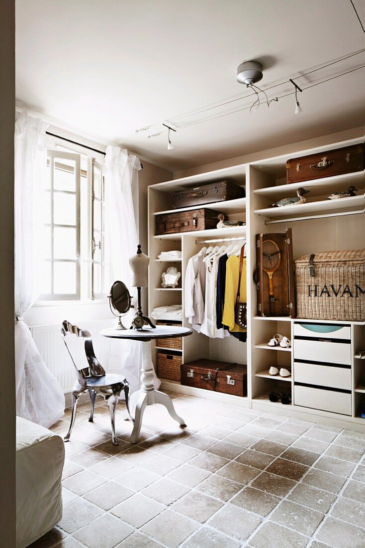 Round table with makeup mirror and postmodern, metal chair in open-plan dressing room