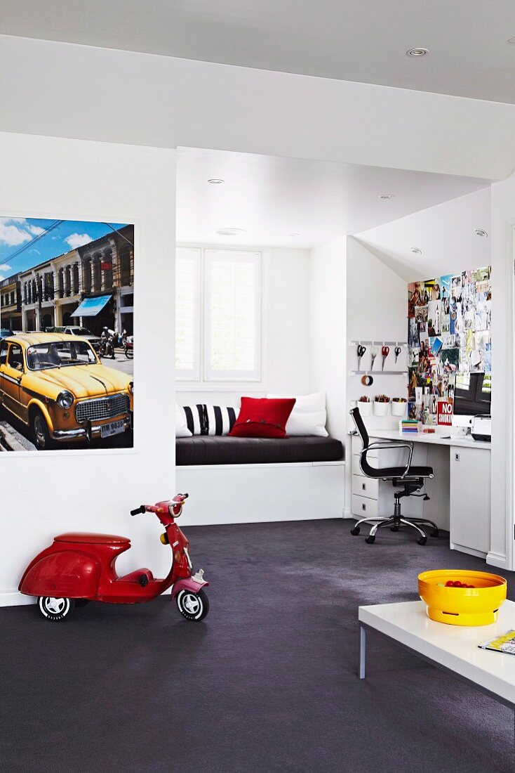 Teenager's bedroom with window seat in niche, study area with wall covered in cuttings and classic swivel chair; red toy Vespa below poster of yellow vintage car