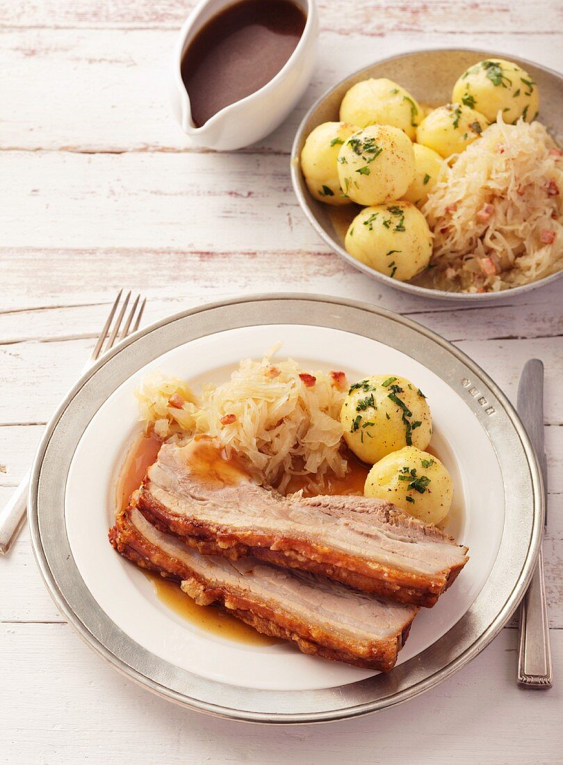 Crackling roast belly of pork, sliced and served with sauerkraut and potato dumplings
