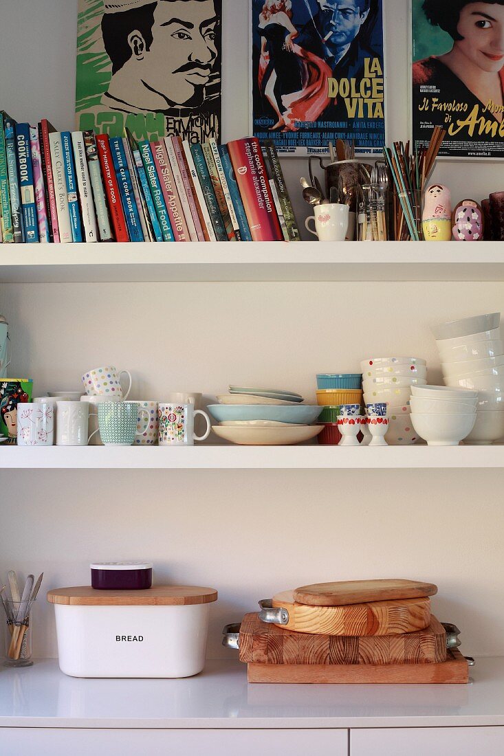 Wooden boards on kitchen base unit below books and crockery on shelves below film posters