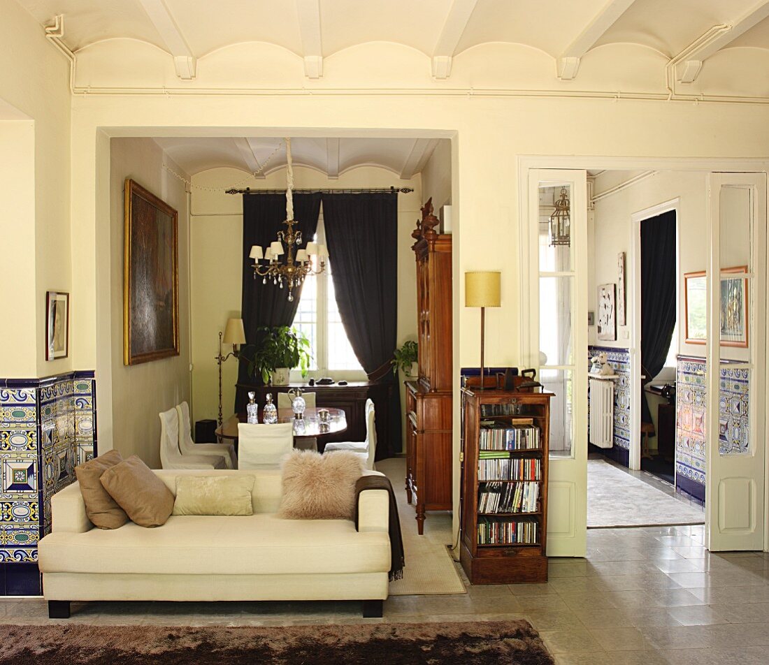 Grand interior with classic sofa in front of open-plan dining area and view into kitchen through open double doors