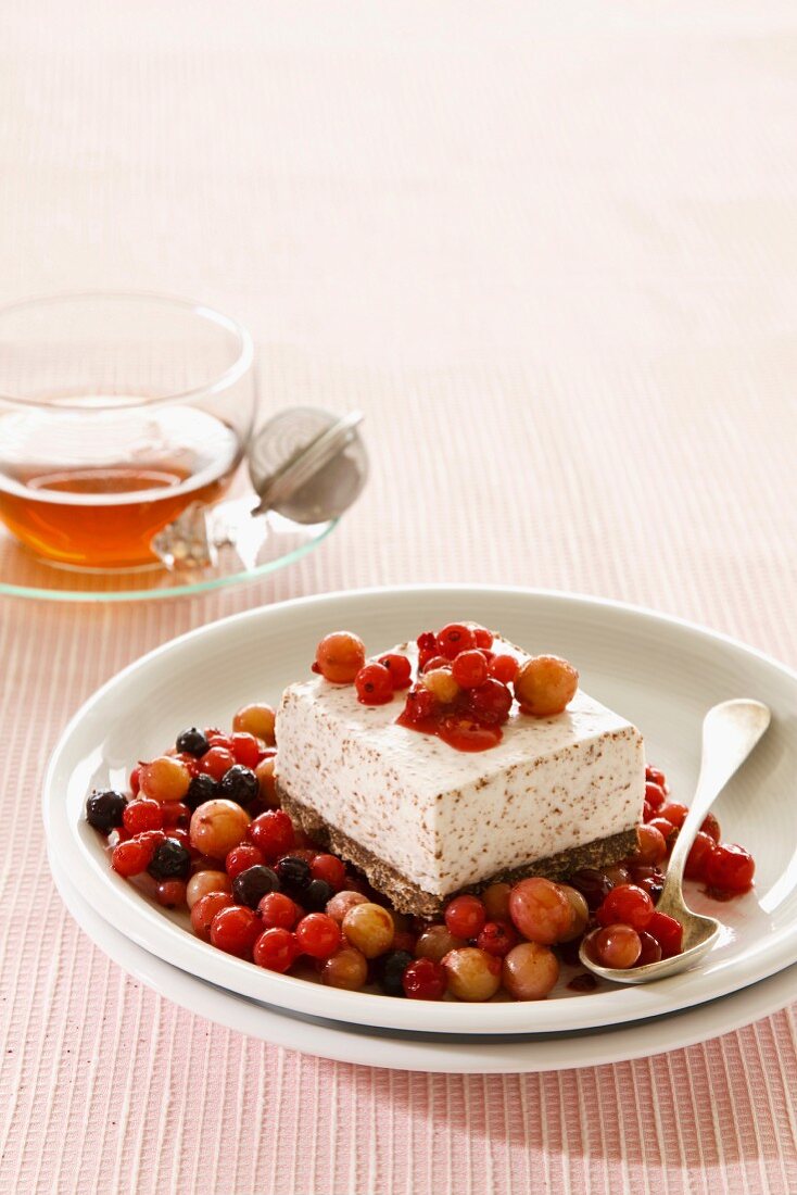A slice of ice cream cake on stewed berries