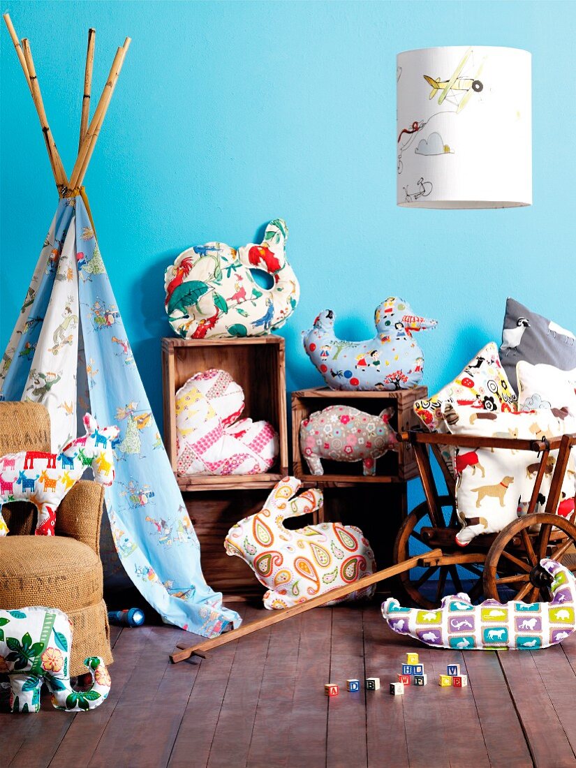 Bright, patterned fabrics in child's bedroom made into stylised animal-shaped cushions, lampshade and indoor teepee