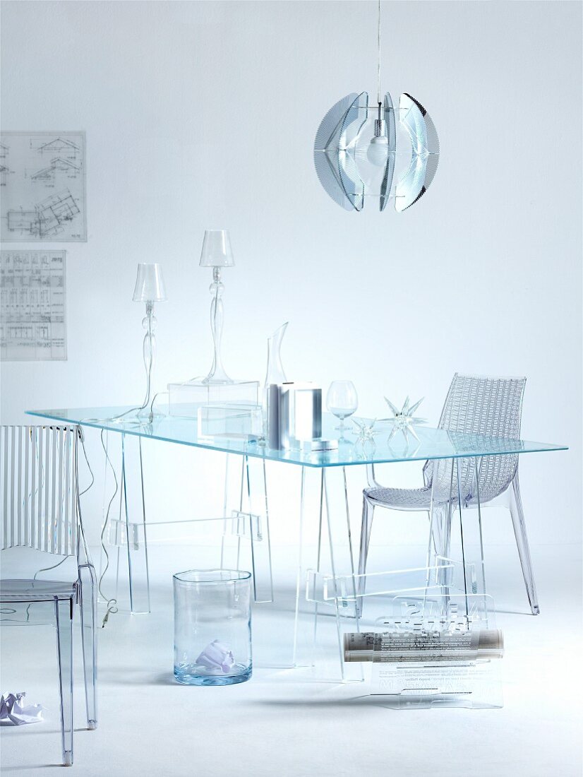 Transparenz - Acrylglas Stühle vor Glastisch und Tischleuchten mit Glasschirm unter kugelförmiger Hängeleuchte aus Metall