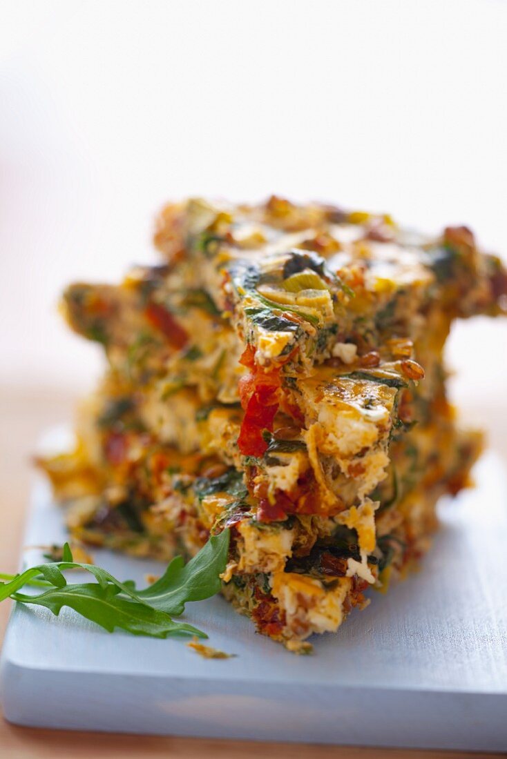 A portion of vegetable frittata with spinach, leek, sundried tomatoes and onions