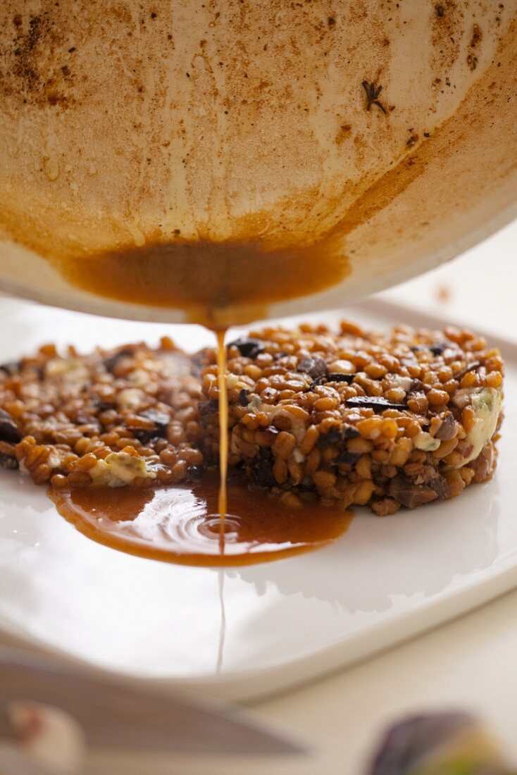 Sauce being poured over oat risotto with mushrooms and blue cheese