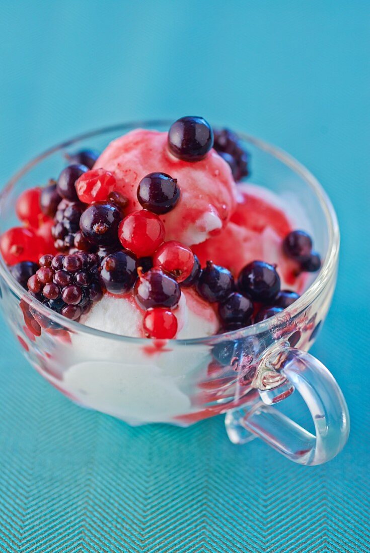 Lemon ice cream with berries in a glass teacup