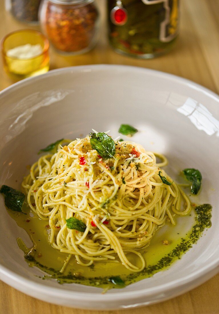 A Mediterranean pasta dish consisting of a spaghetti nest with pesto and olive oil in a deep dish