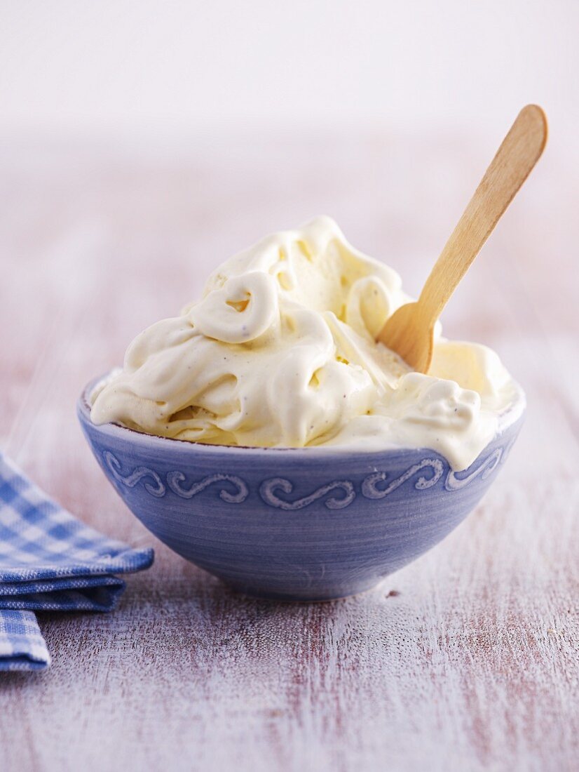 A bowl of melting vanilla ice cream with a wooden spoon