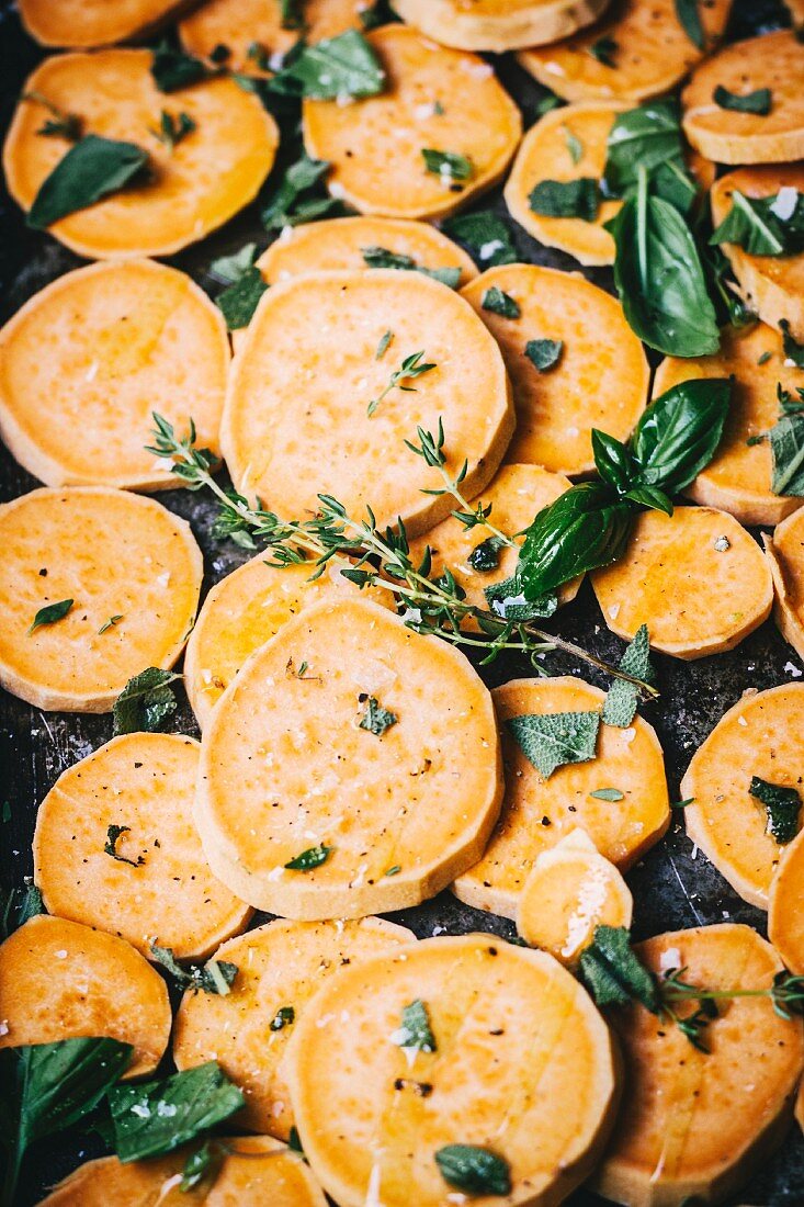 Sweet potato slices with herbs on a baking tray