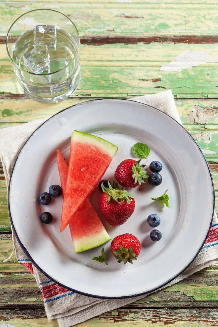 Erdbeeren, Blaubeeren & zwei Melonenstücke auf Teller (Aufsicht)