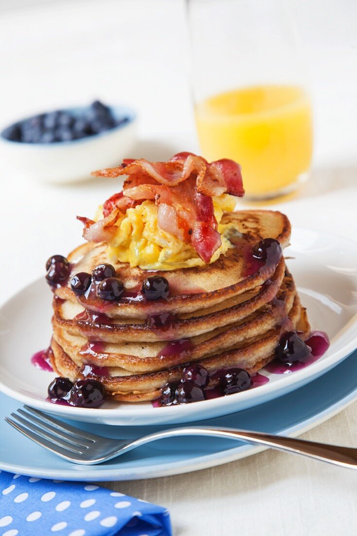 Blueberry Pancakes Topped with Egg and Bacon; Orange Juice