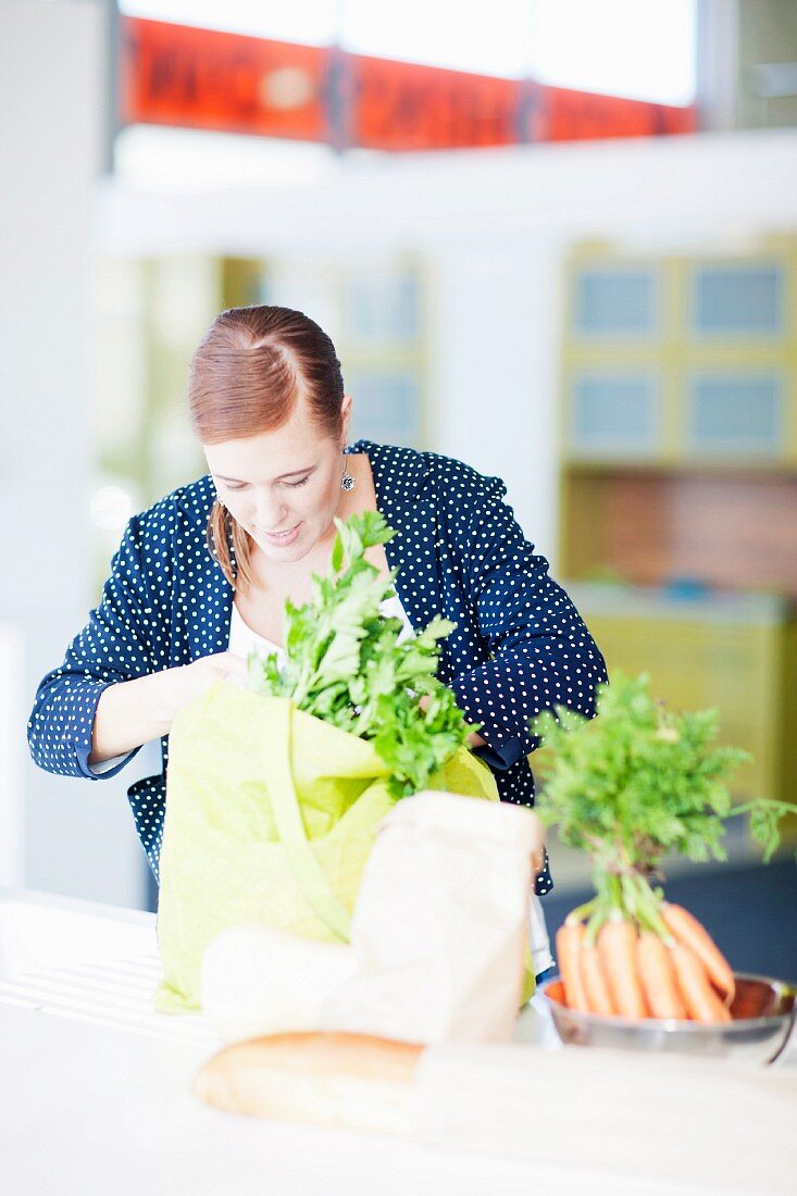 A woman with a bag of shopping in the kitchen