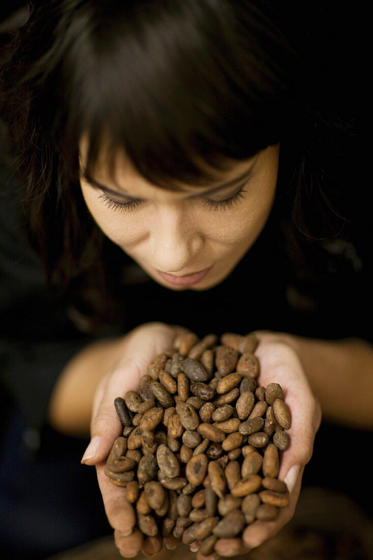A woman holding cocoa beans in her hands