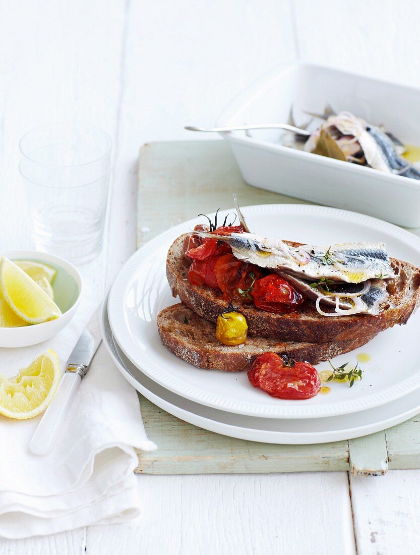 Belegtes Brot mit marinierten Sardinen und zerdrückten gebratenen Kirschtomaten