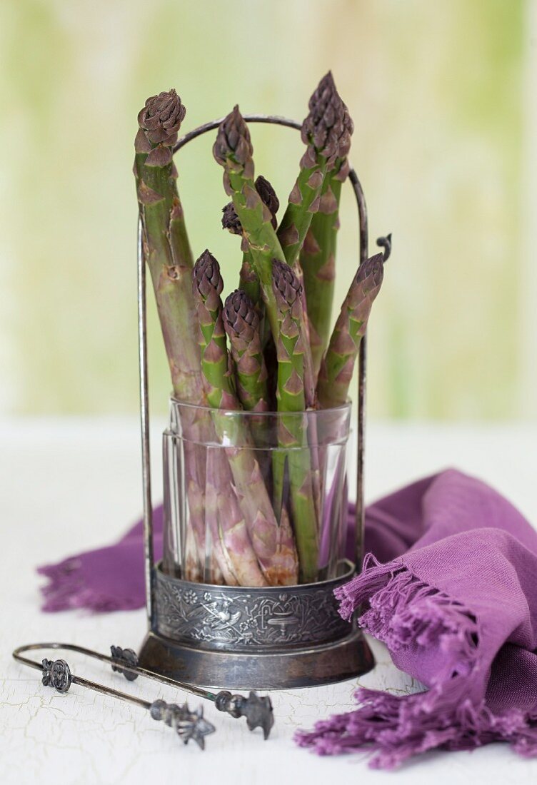 Grüner Spargel in einem Glas, daneben lila Tuch