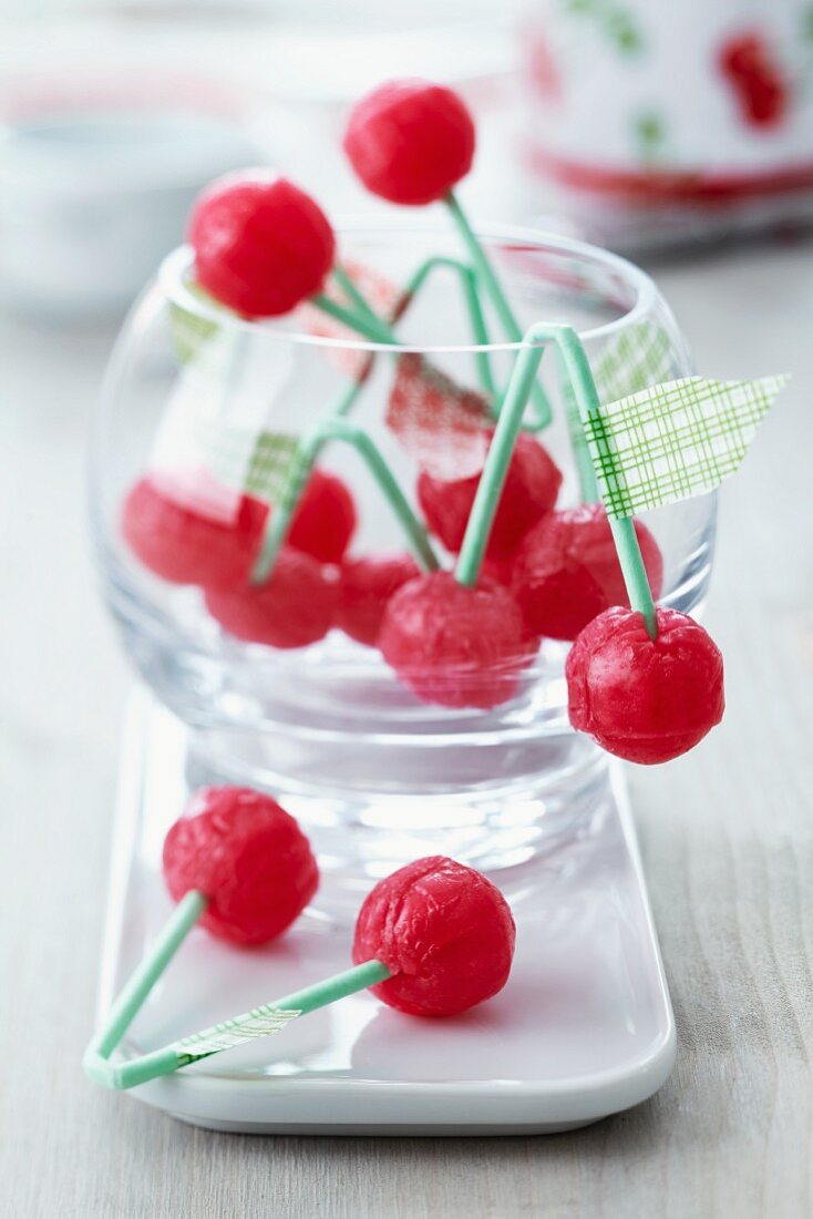 Cherry lollies with masking tape leaves on a round glass bowl