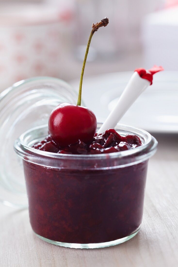 A jar of cherry jam on a breakfast table