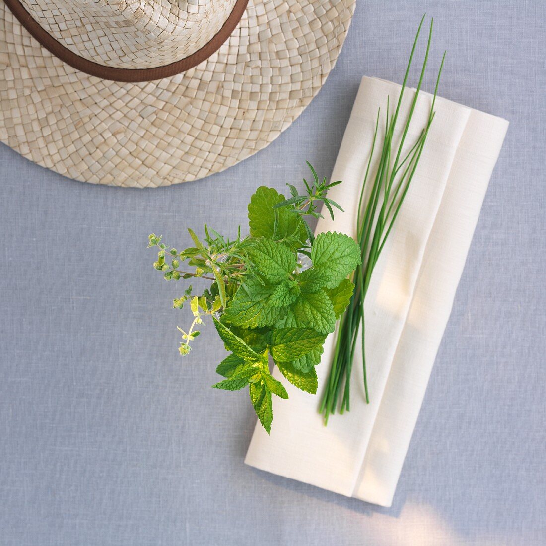 Fresh garden herbs with a napkin and a straw hat