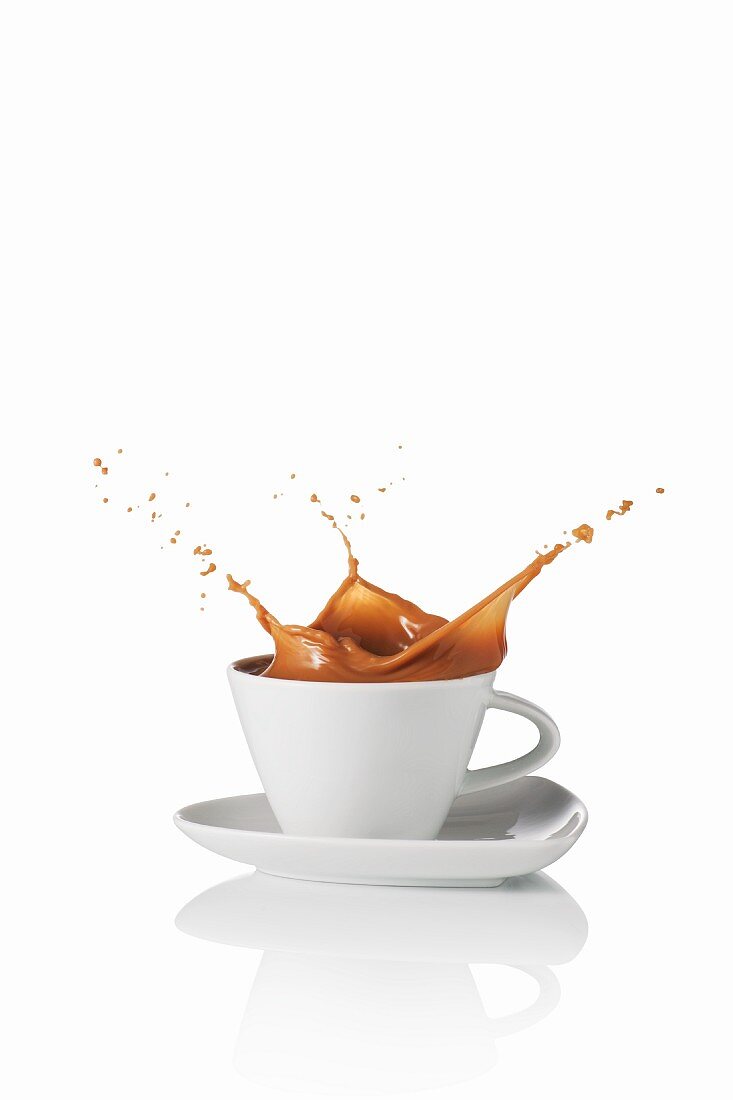 Milchkaffee spritzt aus der Tasse