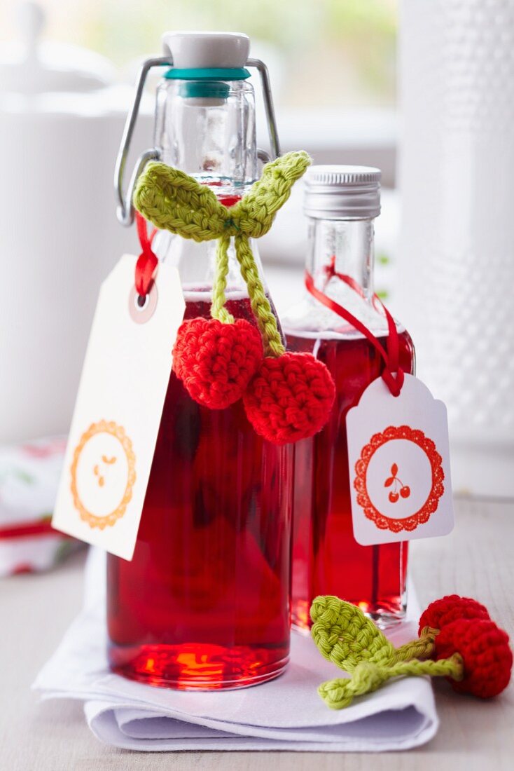 Kirschlikör in kleinen Flaschen dekoriert mit gehäkelten Kirschanhängern und bestempelten Kärtchen