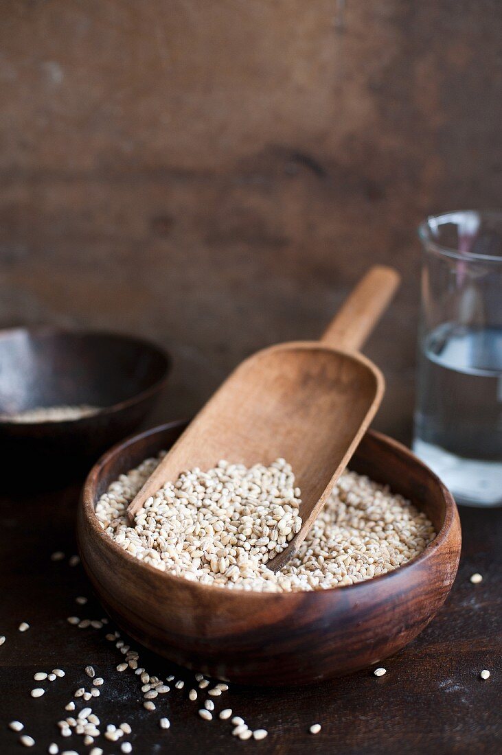 Pearl barley in a wooden bowl with a shovel