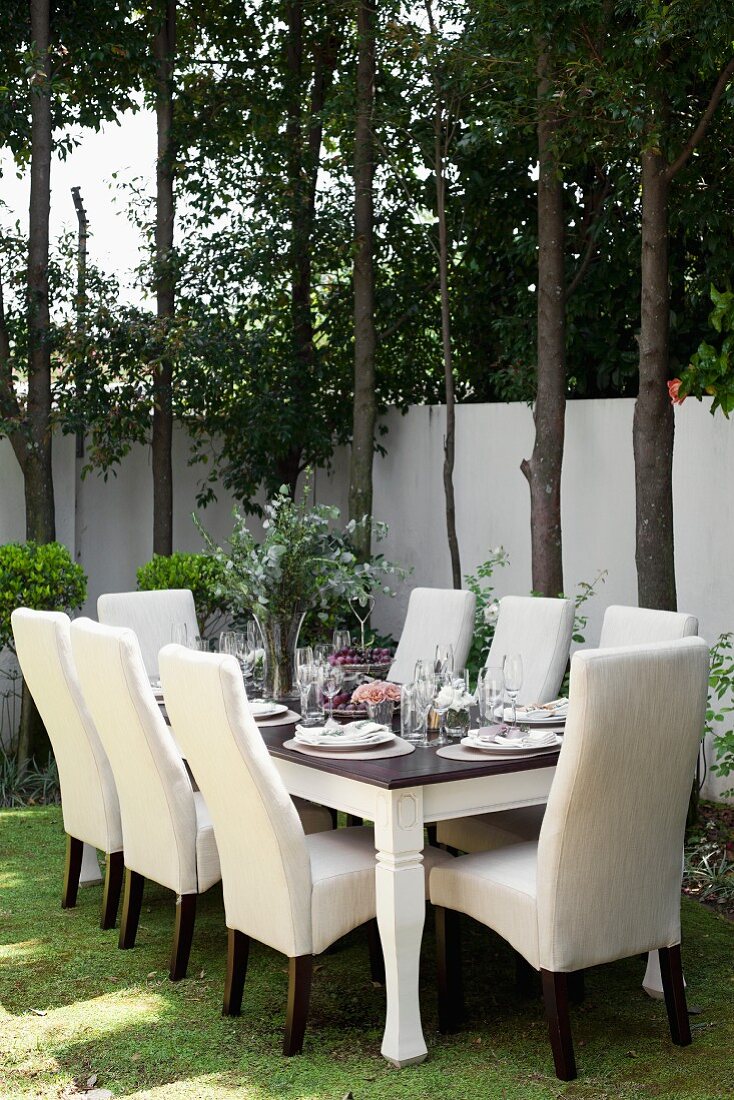 A festively laid table in a garden with white chairs