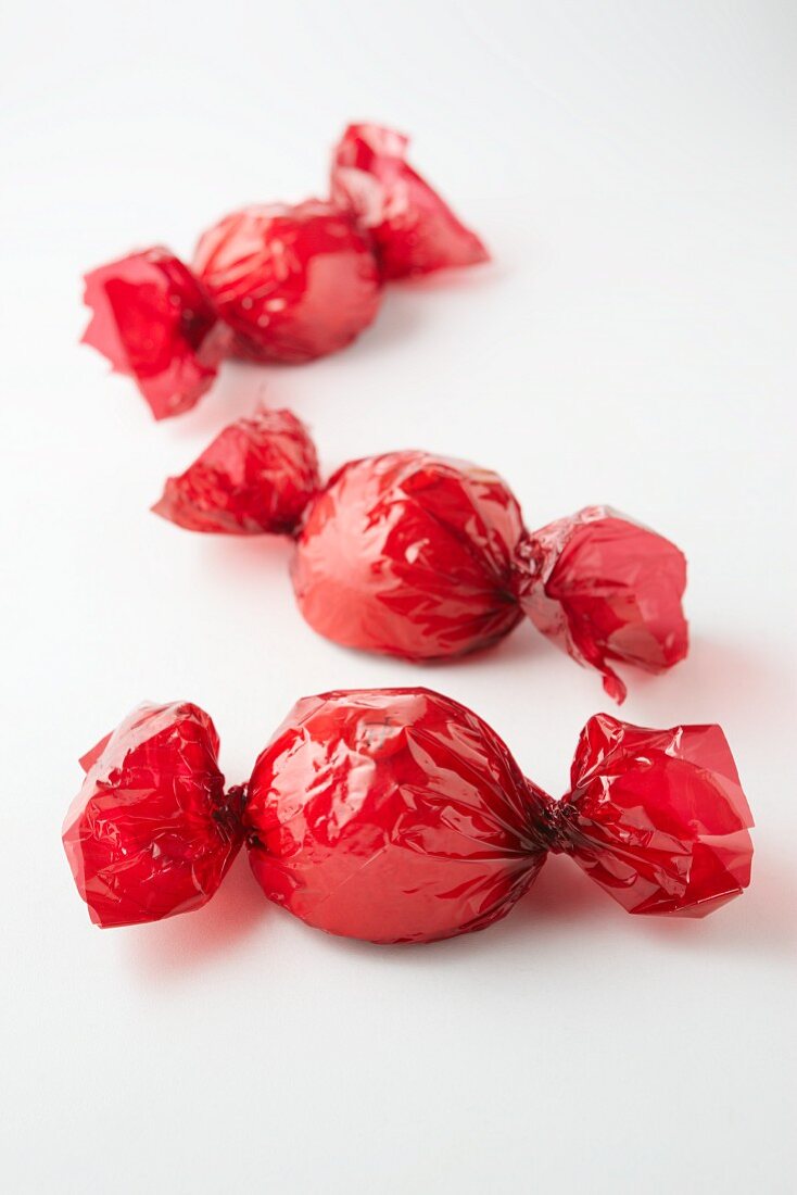 Baisergebäck (Erdbeere, Rhabarber, Passionsfrucht) im roten Cellophanpapier
