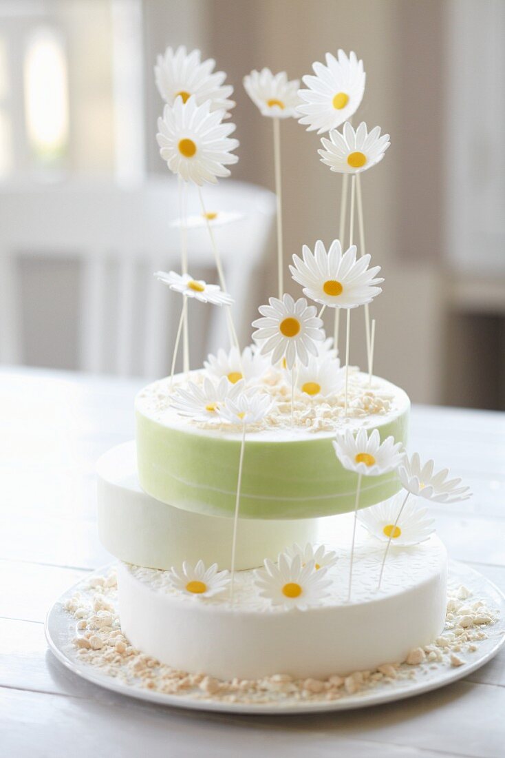 Three-tier lemon layer cake with oxeye daisies