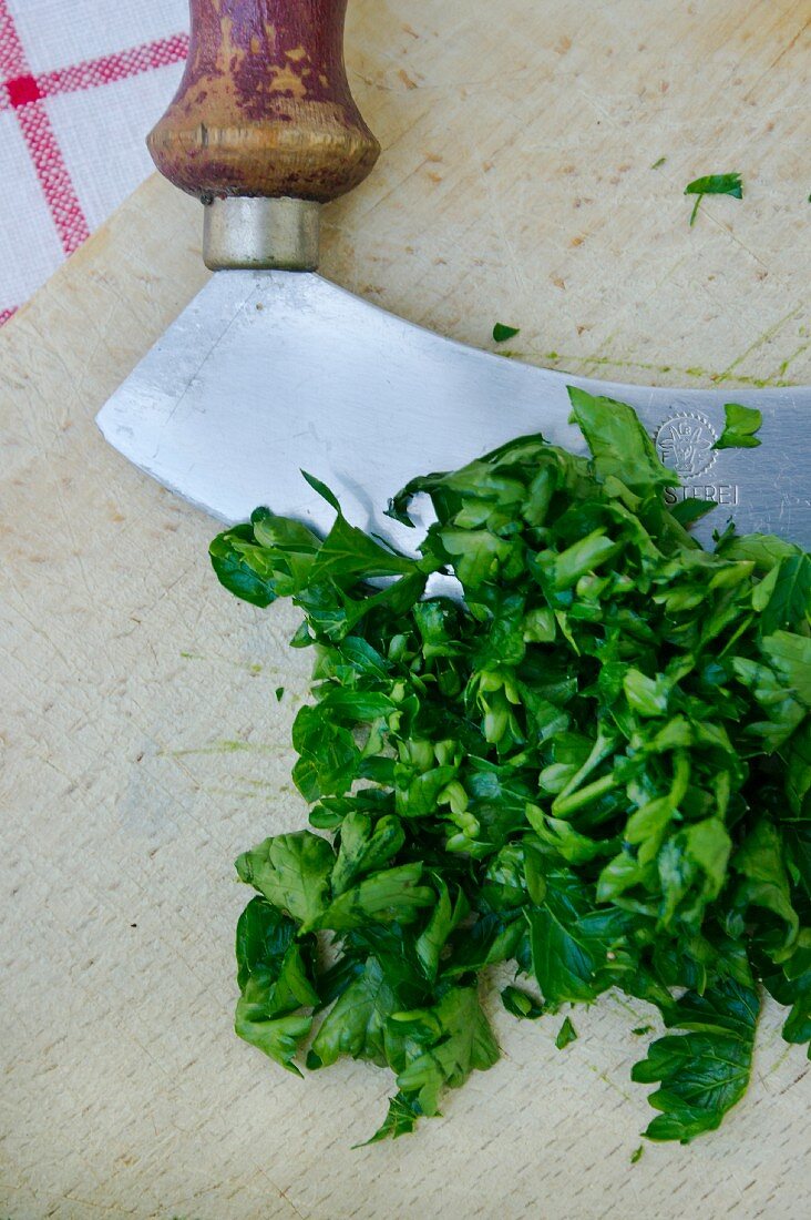 Chopped flat-leaf parsley with a mezzaluna on a board